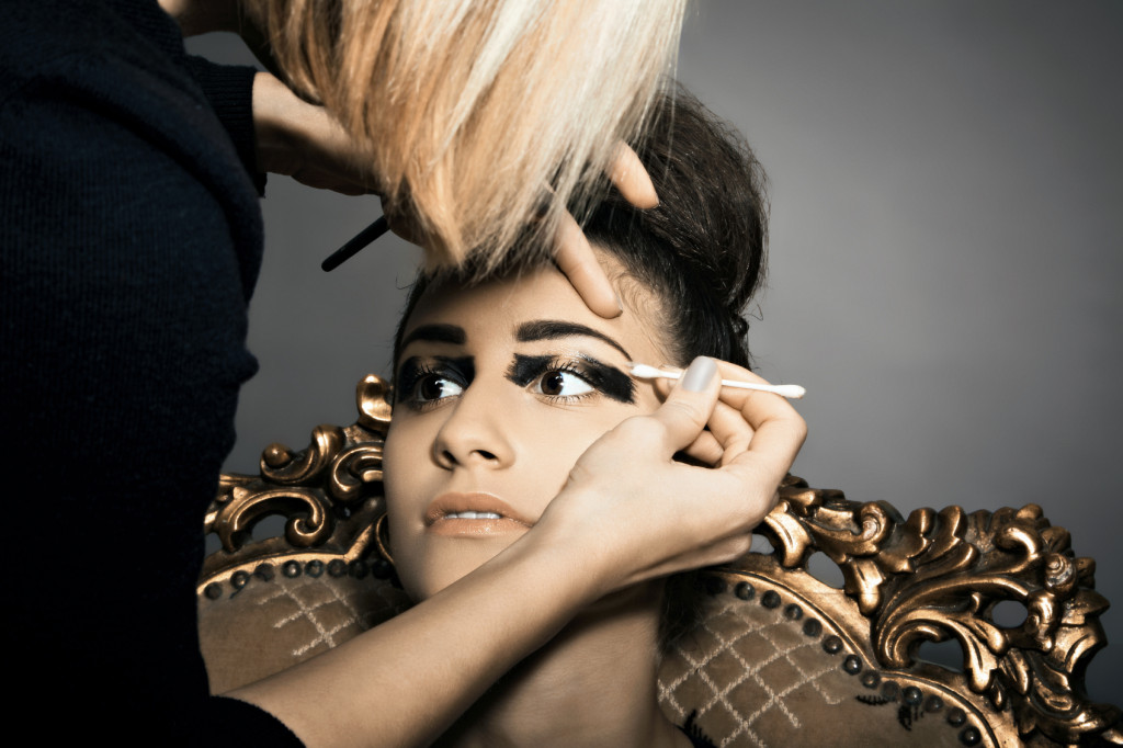 Portrait of young model with make-up artist at work